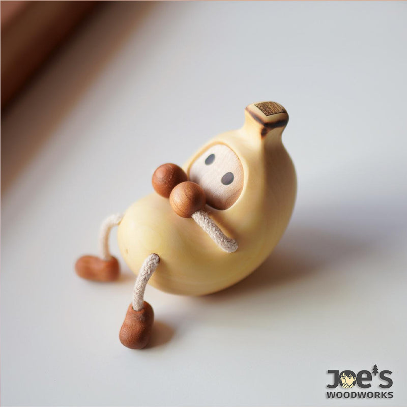 Minimalist banana-shaped wooden character figurine with rope limbs