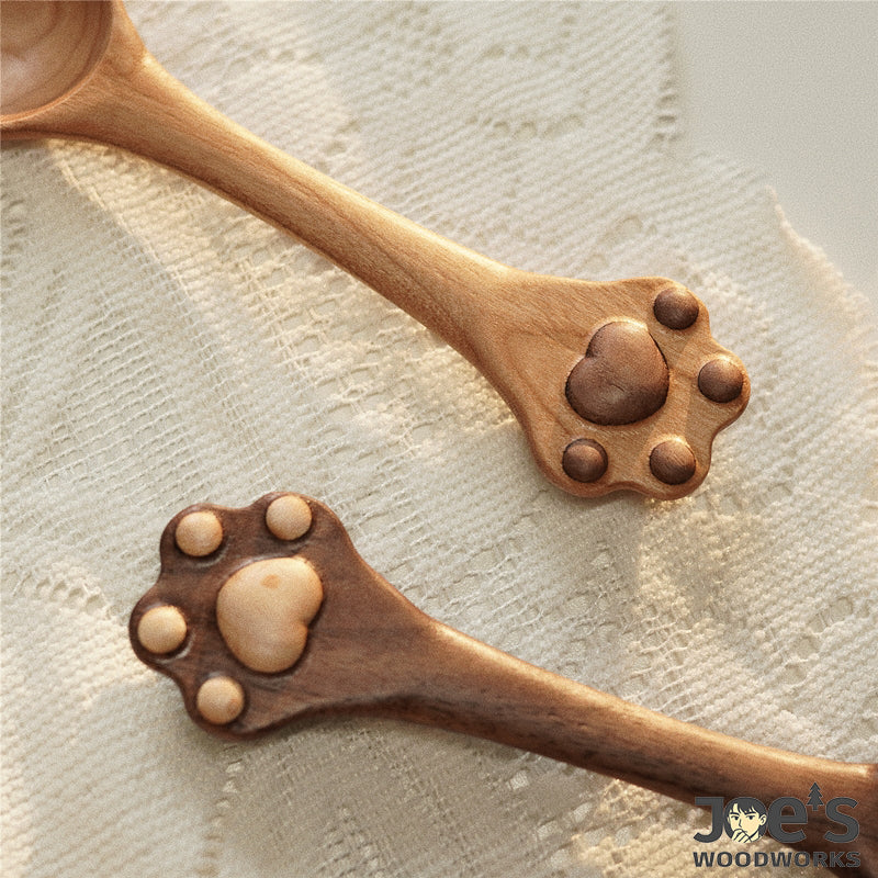 Two cat paw wooden spoons on fabric with soft sunlight