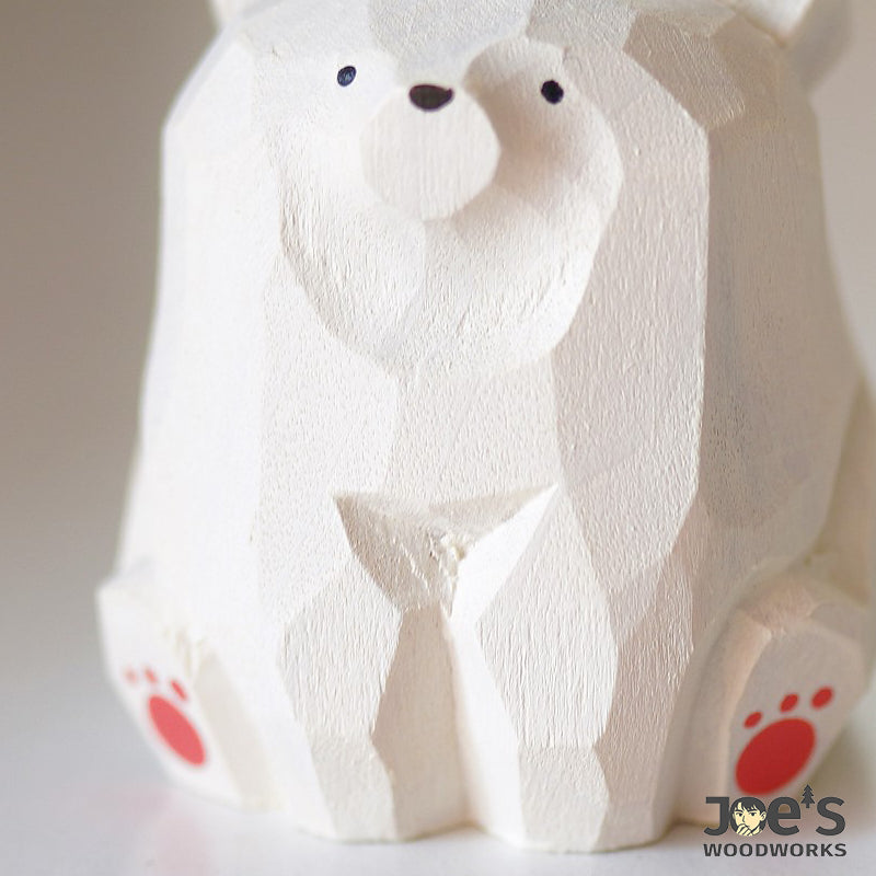 Close-up of polar bear wood figurine showing hand-carved texture and red paw details