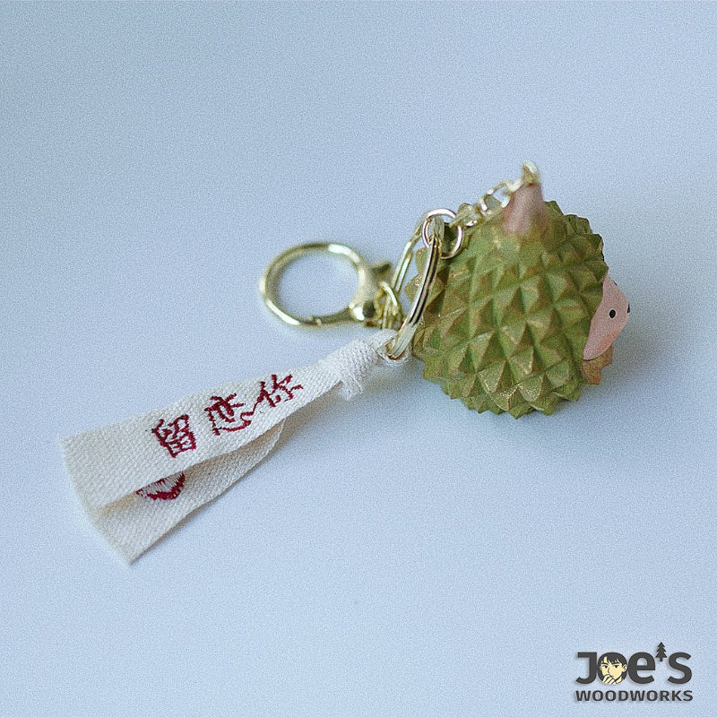 Back side of durian animal wood keychain showing fabric charm tag