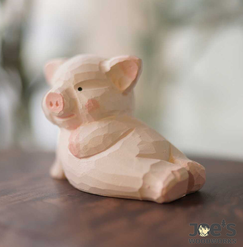 Side view of pink piglet figurine in cherry wood with relaxed pose