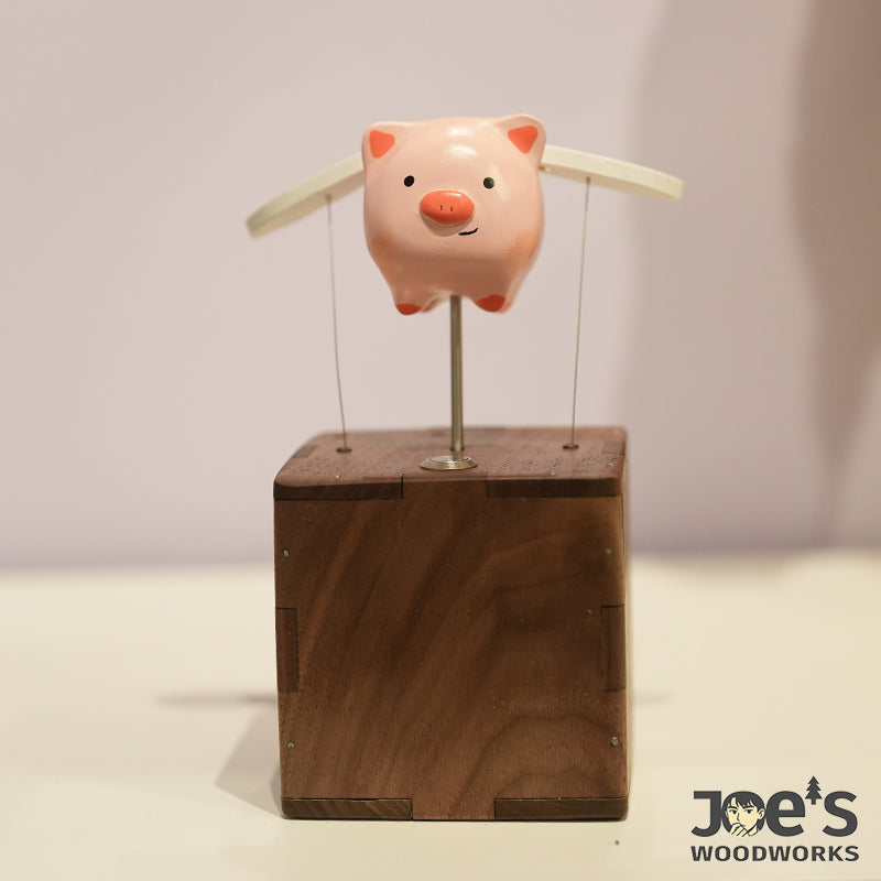 Front view of the smiling pink pig automaton on wood block