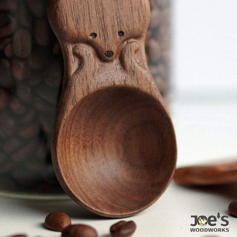 Close-up of dark wood fox coffee scoop showing hand-carved grain and facial details