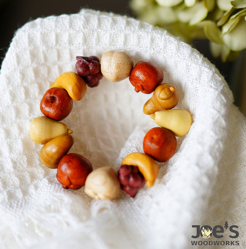 Natural wood fruit charm bracelet resting on soft fabric background
