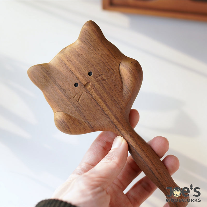 Hand holding cat-shaped wooden hair brush, showing smooth ergonomic grip