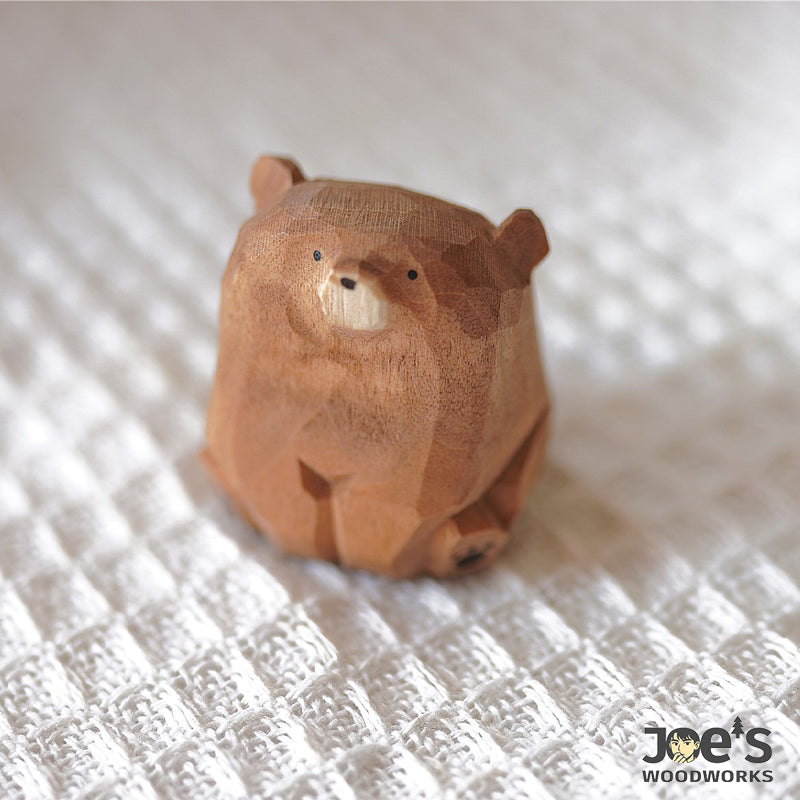 Cute hand-carved brown bear wood sculpture on textured fabric