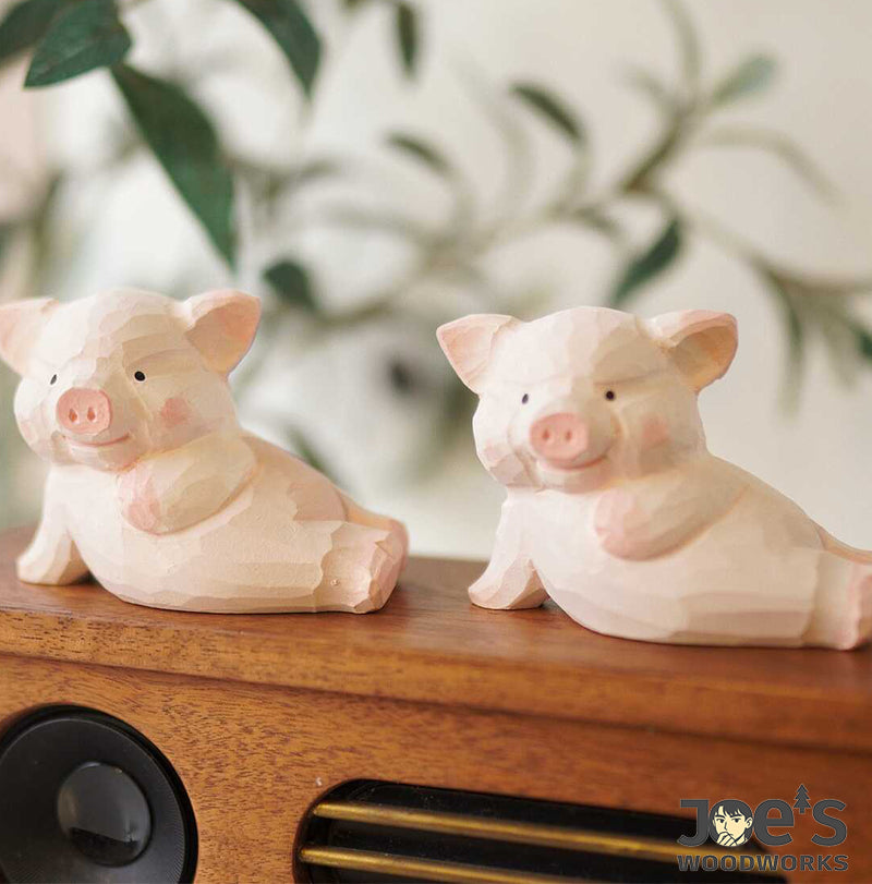 Two pink piglet wooden figurines placed on a wooden speaker shelf