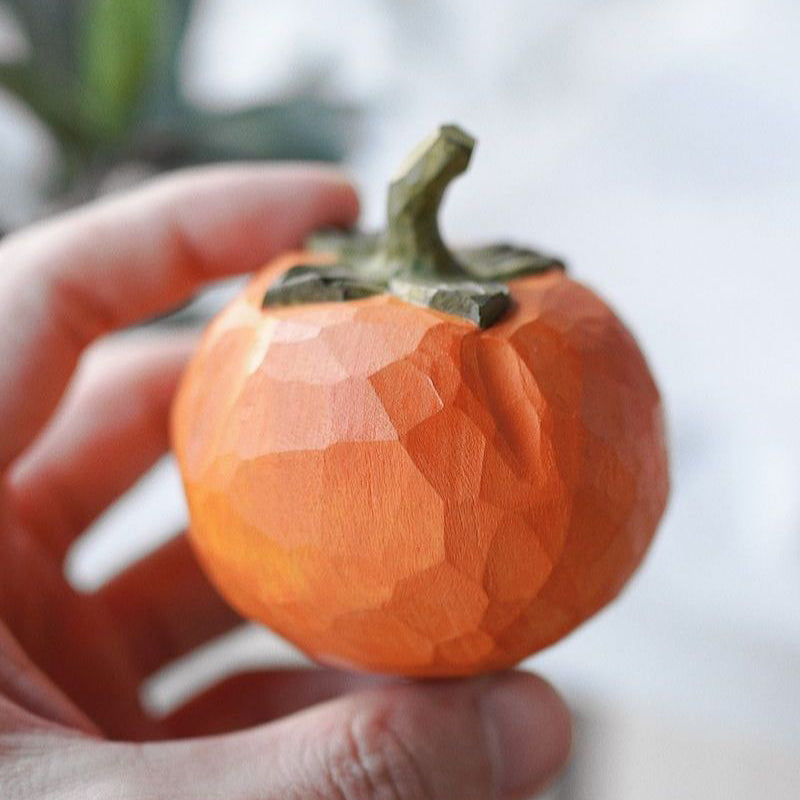 Pipimu Sunny Persimmon wooden ornament with green leaf held in hand