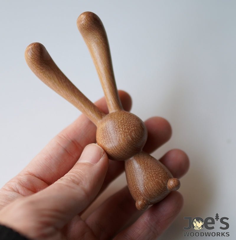 Holding the wooden rabbit massage stick in hand to show scale and shape