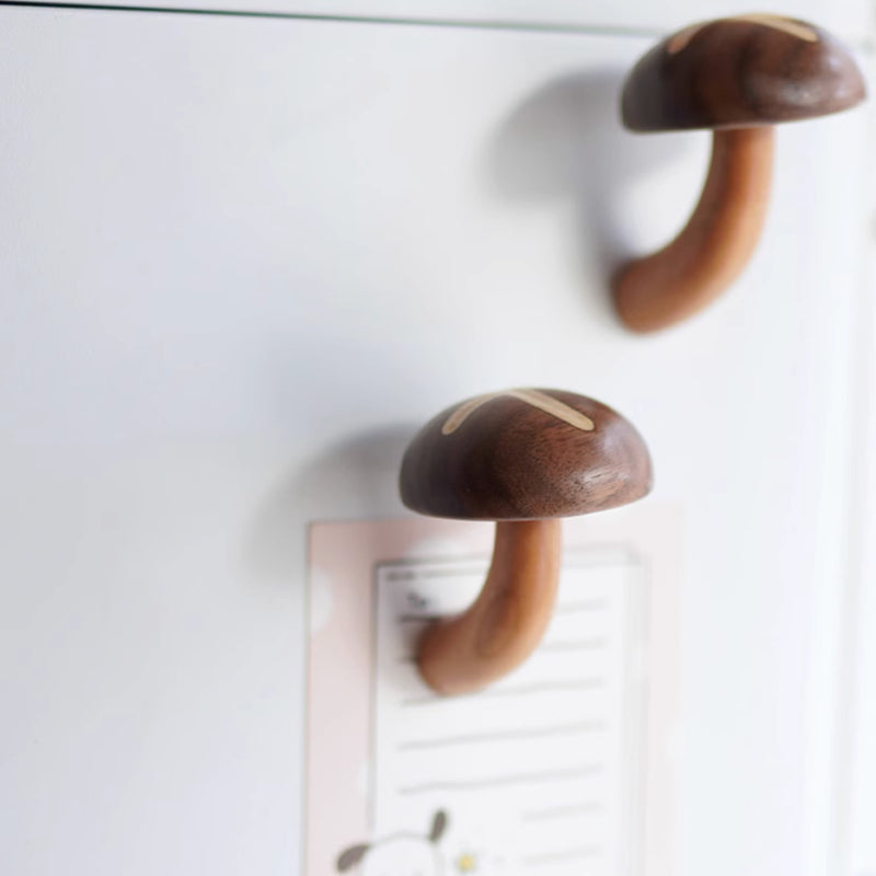 Shiitake mushroom-shaped wood magnets attached to fridge holding a note