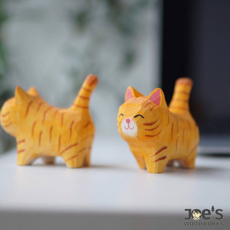Close-up of a small orange striped cat figurine, handcrafted with a happy face
