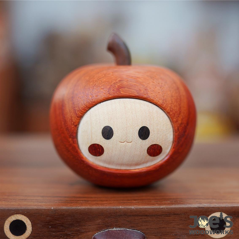 Front view of wooden apple figurine with charming face and red cheeks