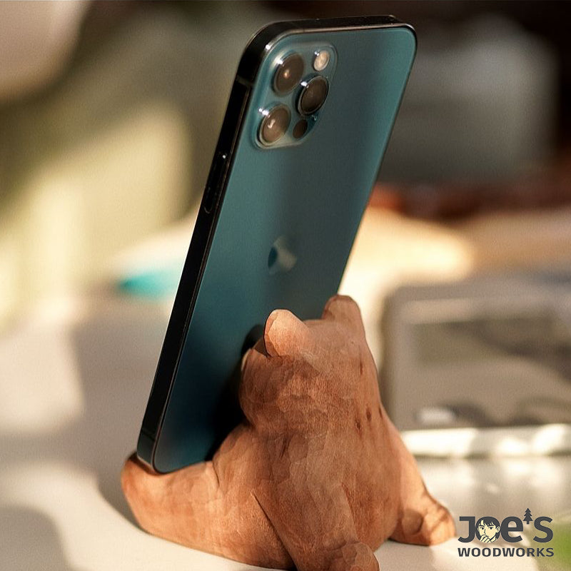 Angled view of carved bear stand propping up a phone