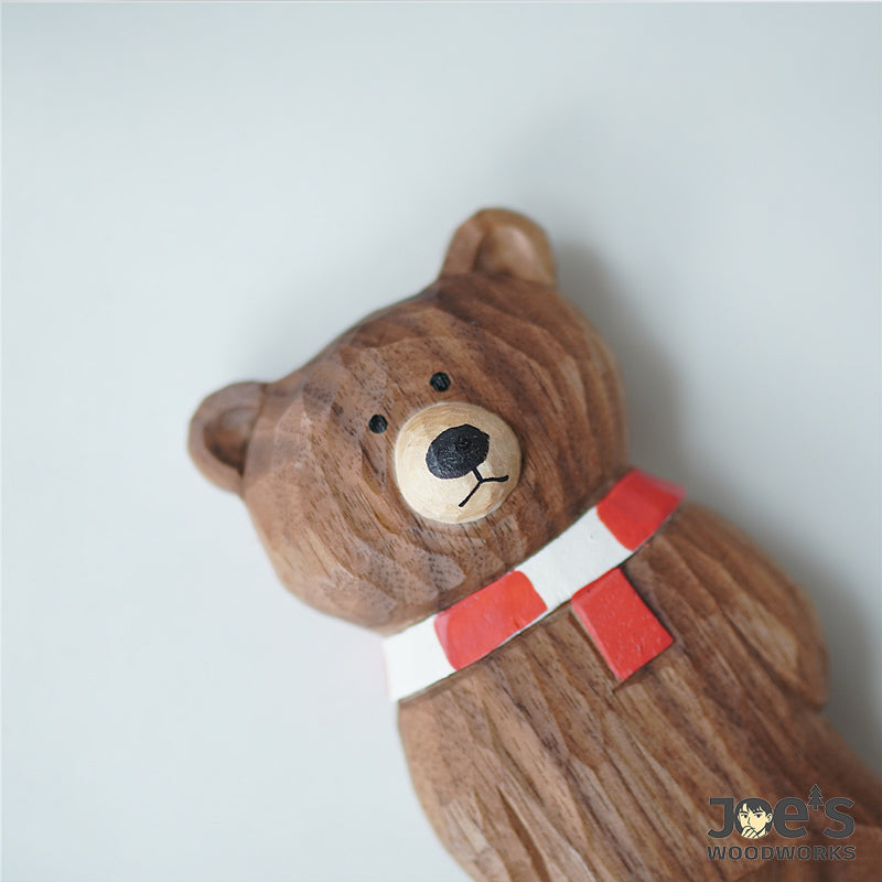 Close-up view of the bearās carved wooden face with red and white scarf.