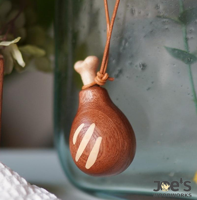 Natural wood drumstick keychain with leather cord, hanging from glass container