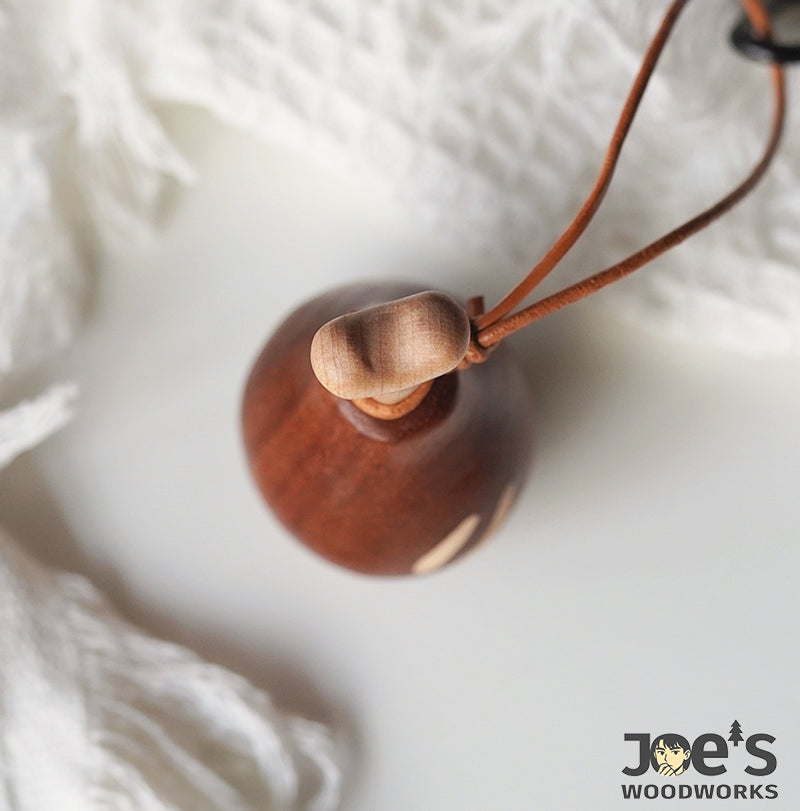 Top view of bone-shaped handle on wooden drumstick keychain with leather strap