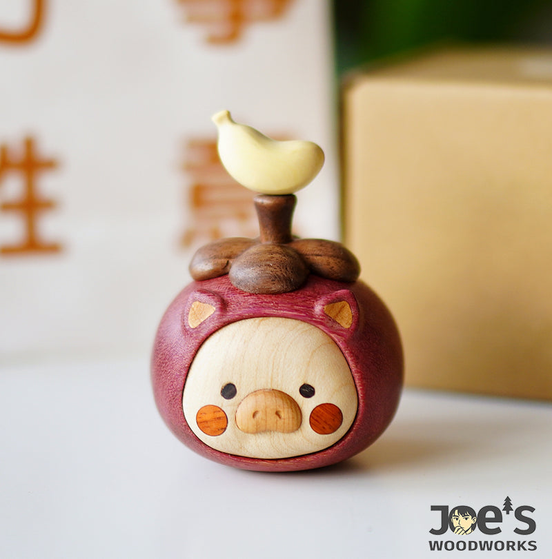 Handmade wooden pig ornament standing upright with banana-shaped topper on wooden fruit cap