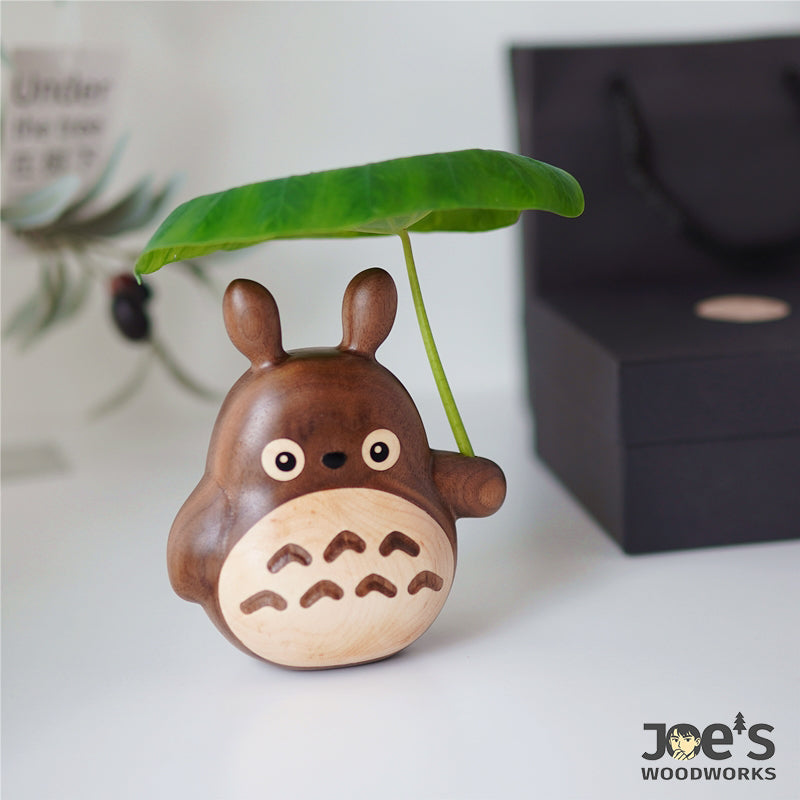Cute wooden Totoro care cat figurine holding a real green leaf, perfect for natural home decor.