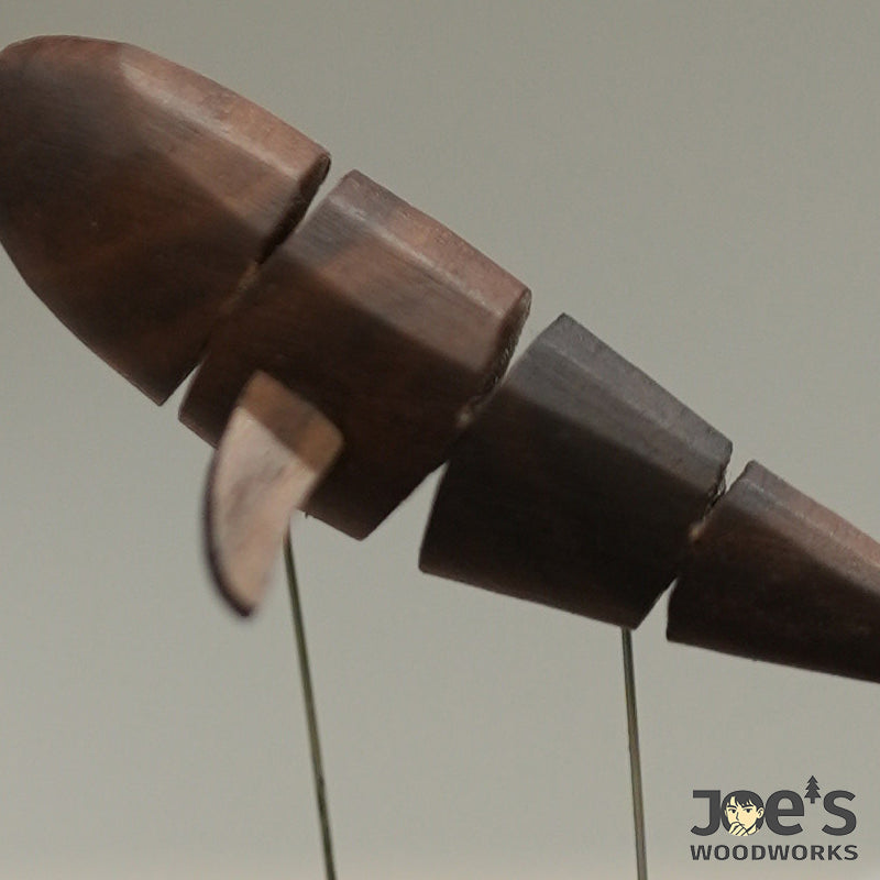 Close-up of segmented whale body with carved fin in walnut wood