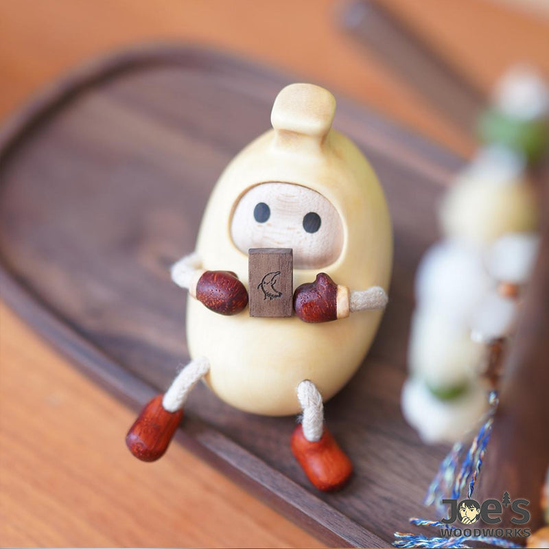 Hand-carved banana wood character holding book – Joe&