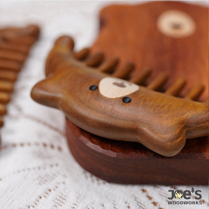 Close-up of bear face carved on wooden massage comb, side angle
