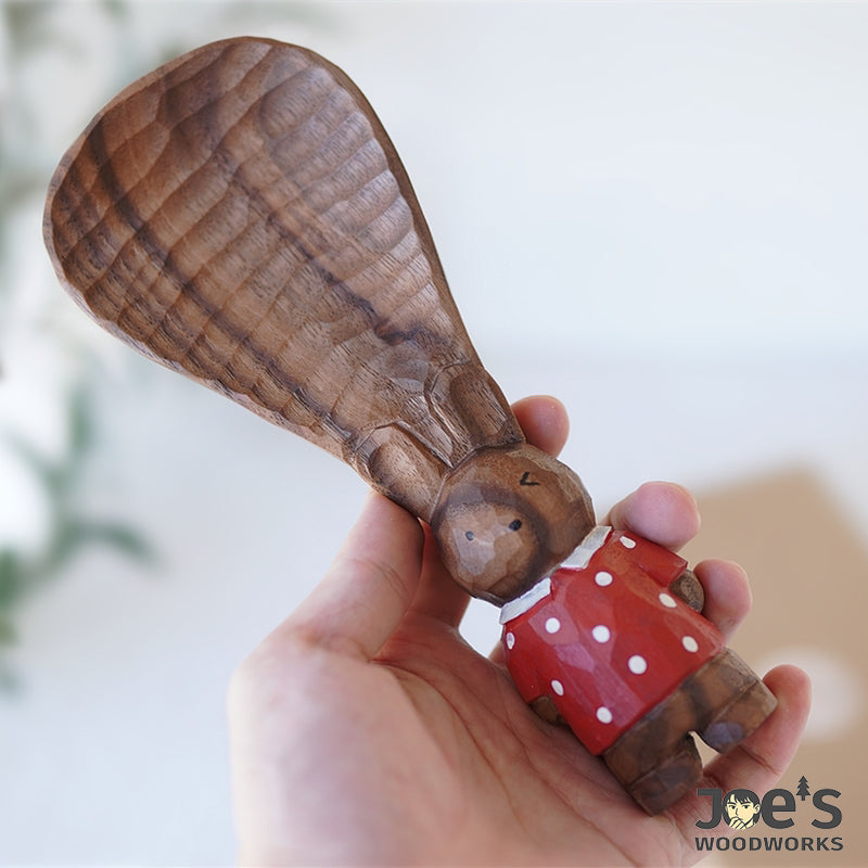 Cute wooden standing bunny rice paddle held in hand, playful gift and kitchen decor.