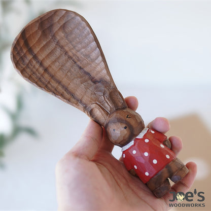 Cute wooden standing bunny rice paddle held in hand, playful gift and kitchen decor.