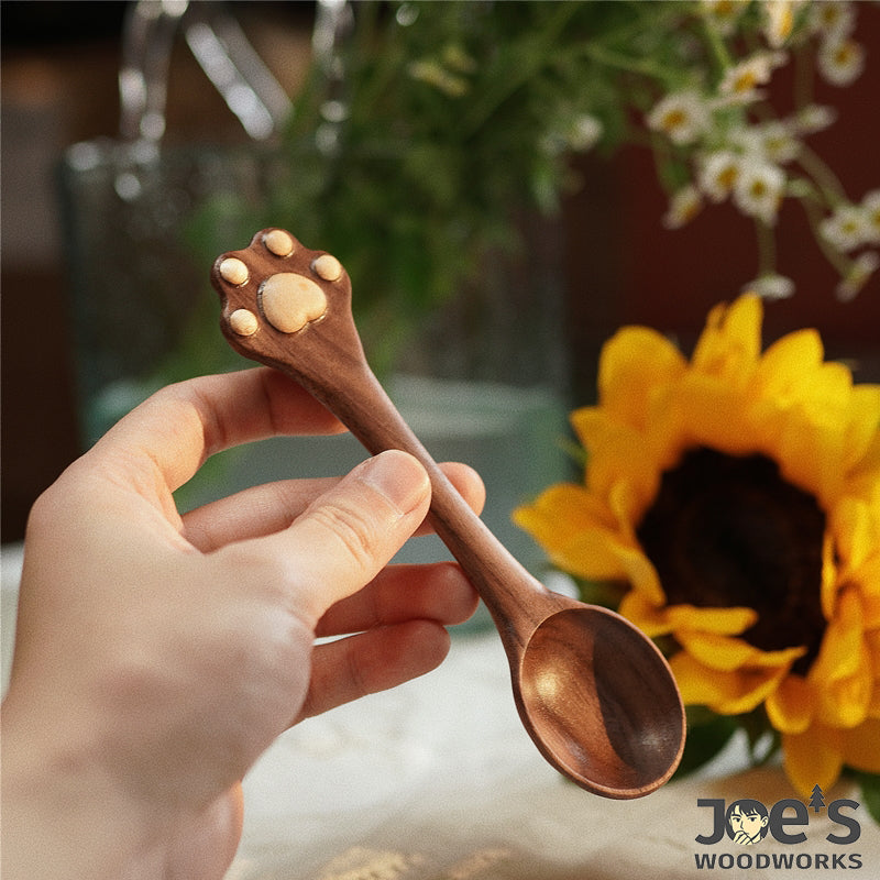 Hand holding dark walnut cat paw spoon with carved paw print