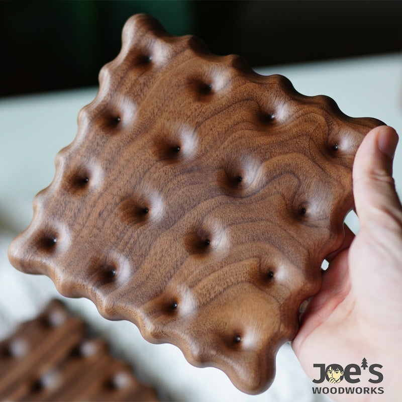 Hand holding biscuit-style walnut coaster with sculpted dimples