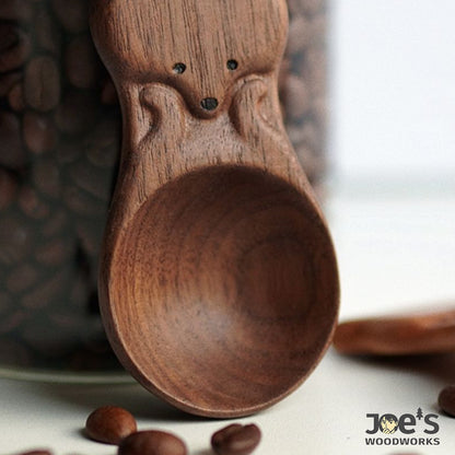 Close-up of dark wood fox coffee scoop showing hand-carved grain and facial details