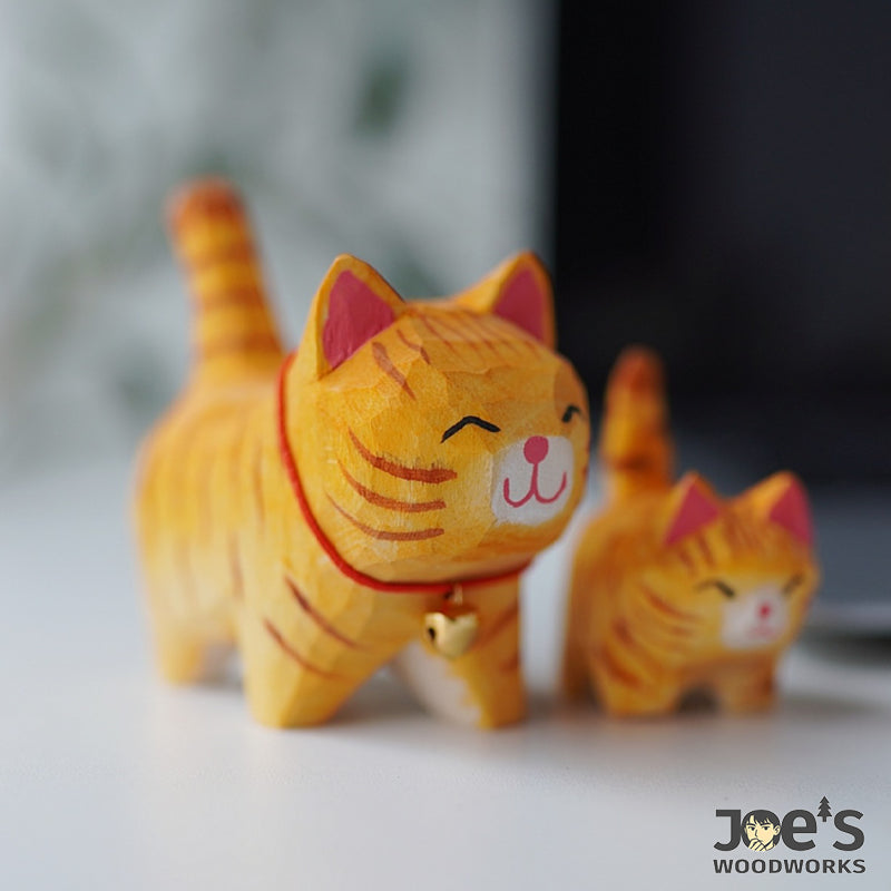 Smiling orange cat with red collar and heart bell, paired with a small kitten figure