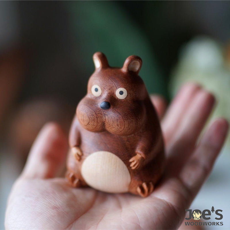 Cute wooden mouse figurine with big eyes and chubby cheeks in palm.
