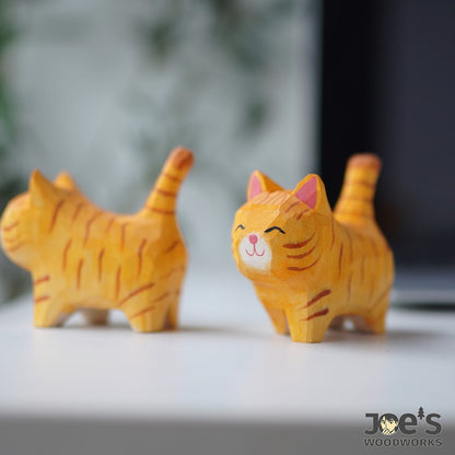Close-up of a small orange striped cat figurine, handcrafted with a happy face