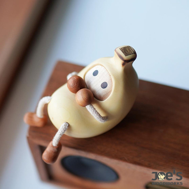 Banana-shaped wood figurine sitting on wooden speaker – cute desk decor idea