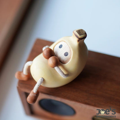 Banana-shaped wood figurine sitting on wooden speaker – cute desk decor idea