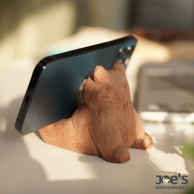 Hand-carved wooden bear stand holding smartphone, stable back view