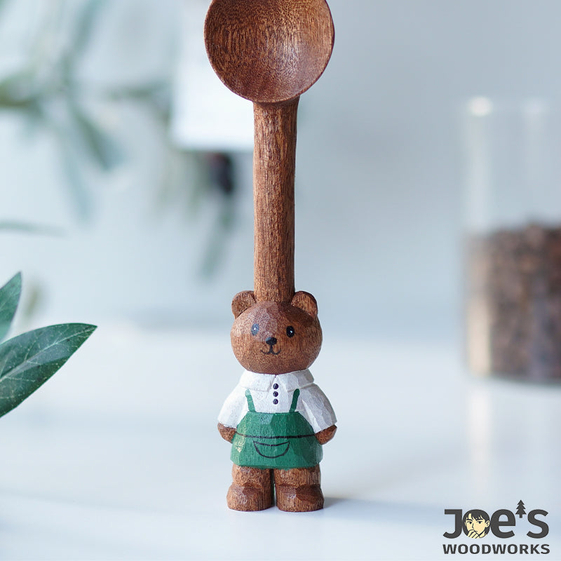 Coffee scoop spoon standing upright, bear in green apron front view